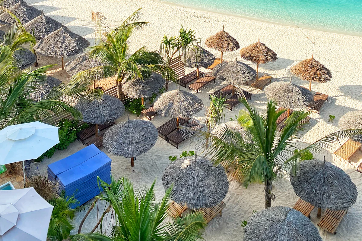 Thatched sunshades and sun loungers on a white sand beach in Zanzibar